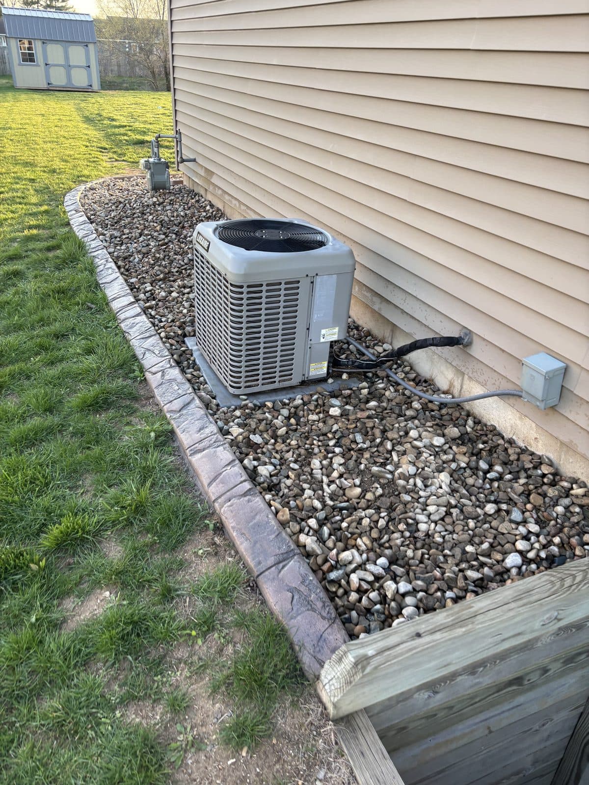 A clean river-rock bed with crisp edging along a home by Fresh Cut Lawns.