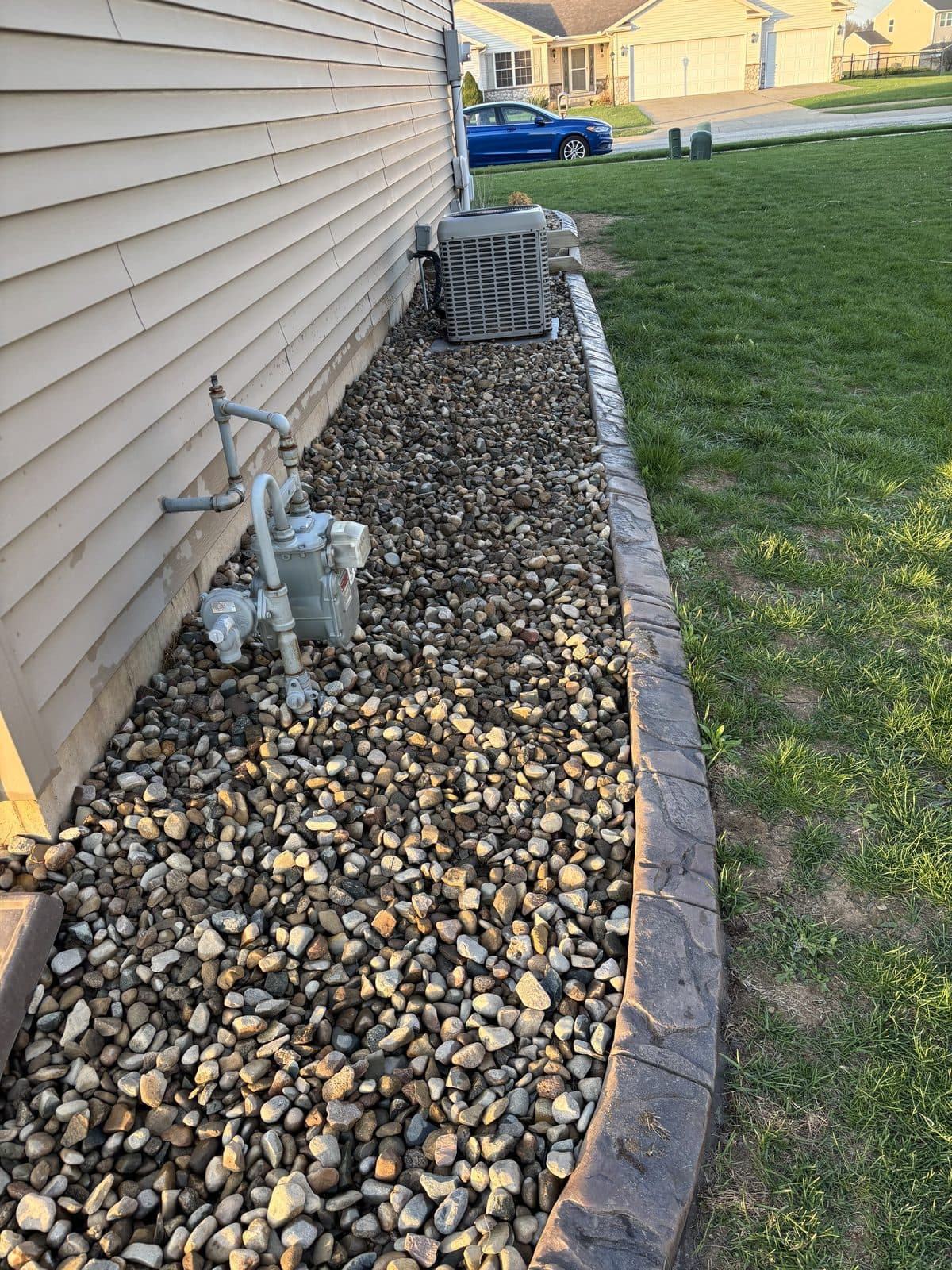 A clean river-rock bed with crisp edging along a home by Fresh Cut Lawns.