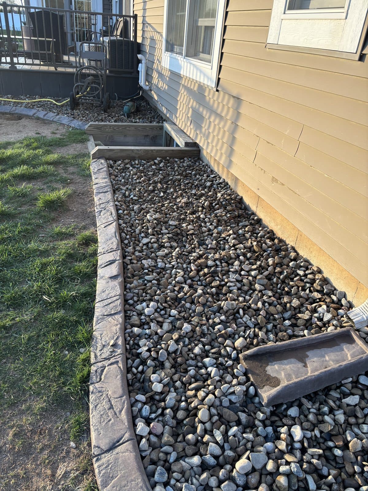 A clean river-rock bed with crisp edging along a home by Fresh Cut Lawns.