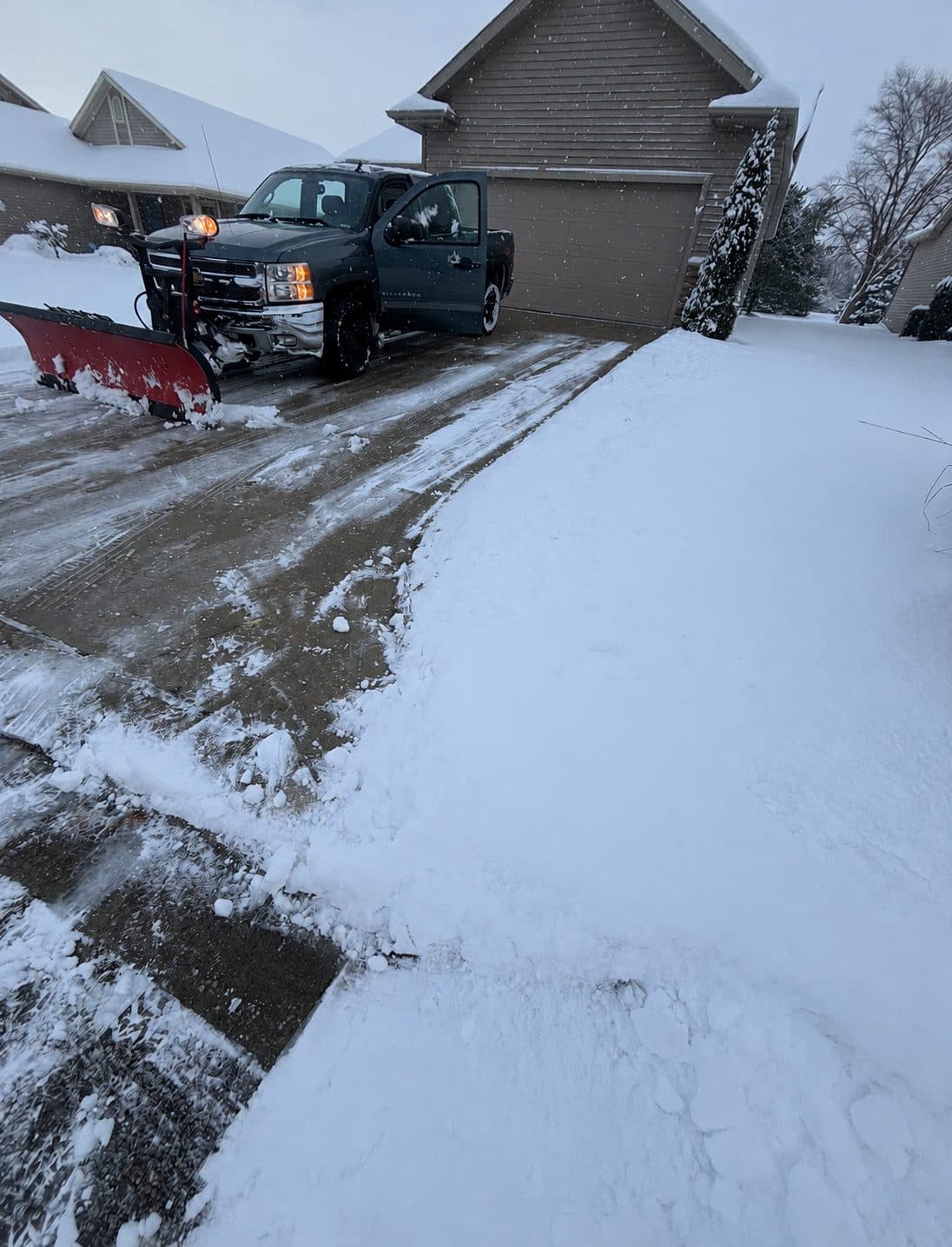 A Fresh Cut Lawns plow truck clearing snow from a residential driveway in winter.